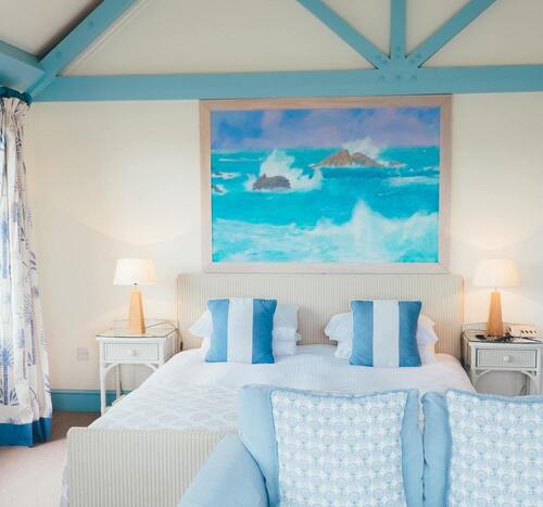 un lit double avec au dessus un tableau de la mer